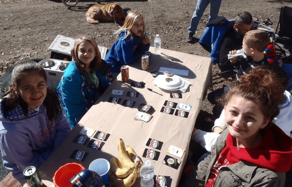 Playing Golf the Card Game at picnic table Children sitting at a table outdoors, smiling and playing card games.